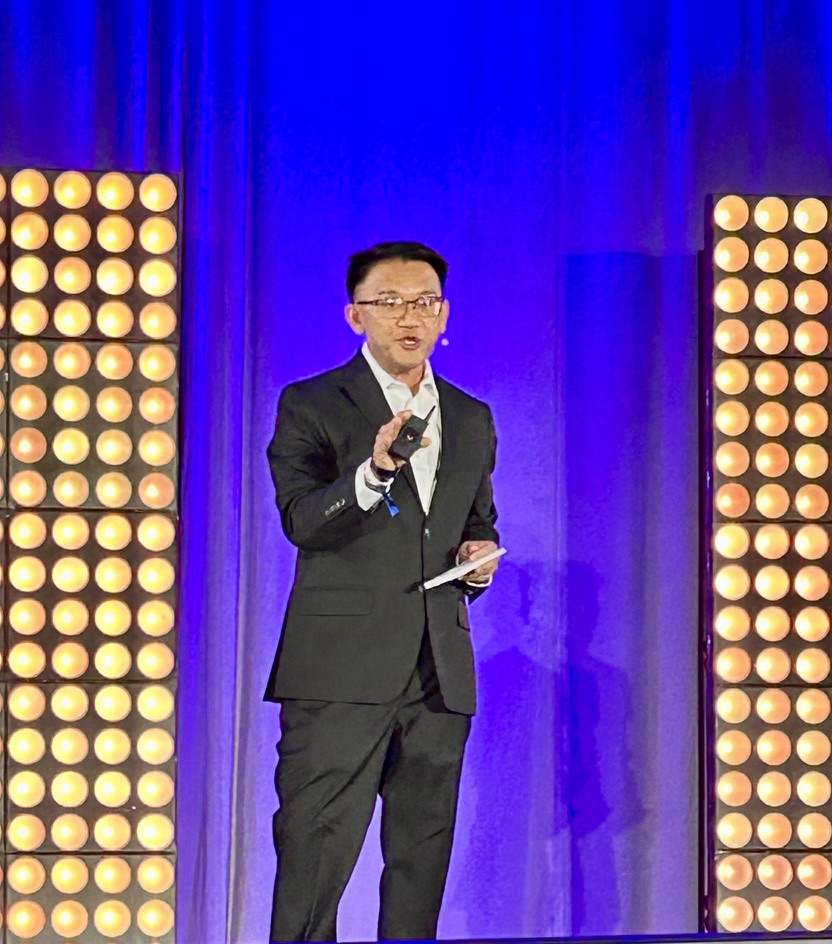 TOON speaking on stage between illuminated panels