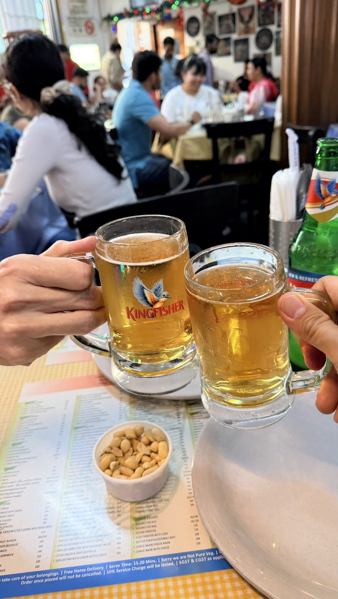 Two Kingfisher beer glasses raised at Leopold Café, Mumbai, India.