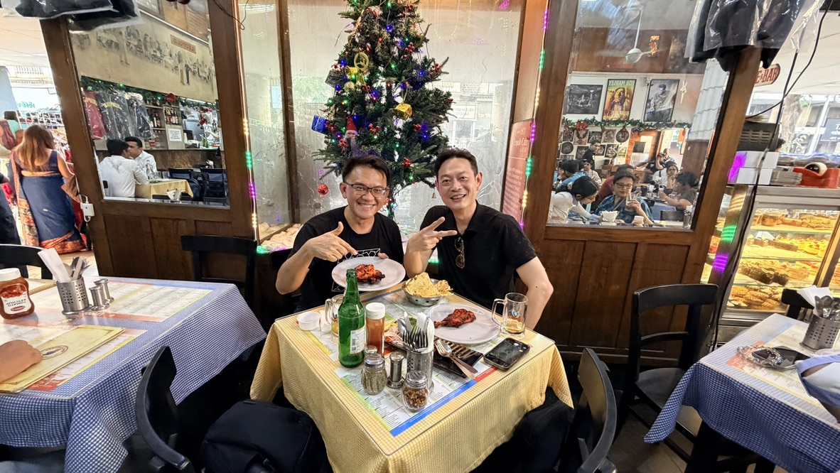 Two travellers sharing lunch at Leopold Café, Mumbai, India.