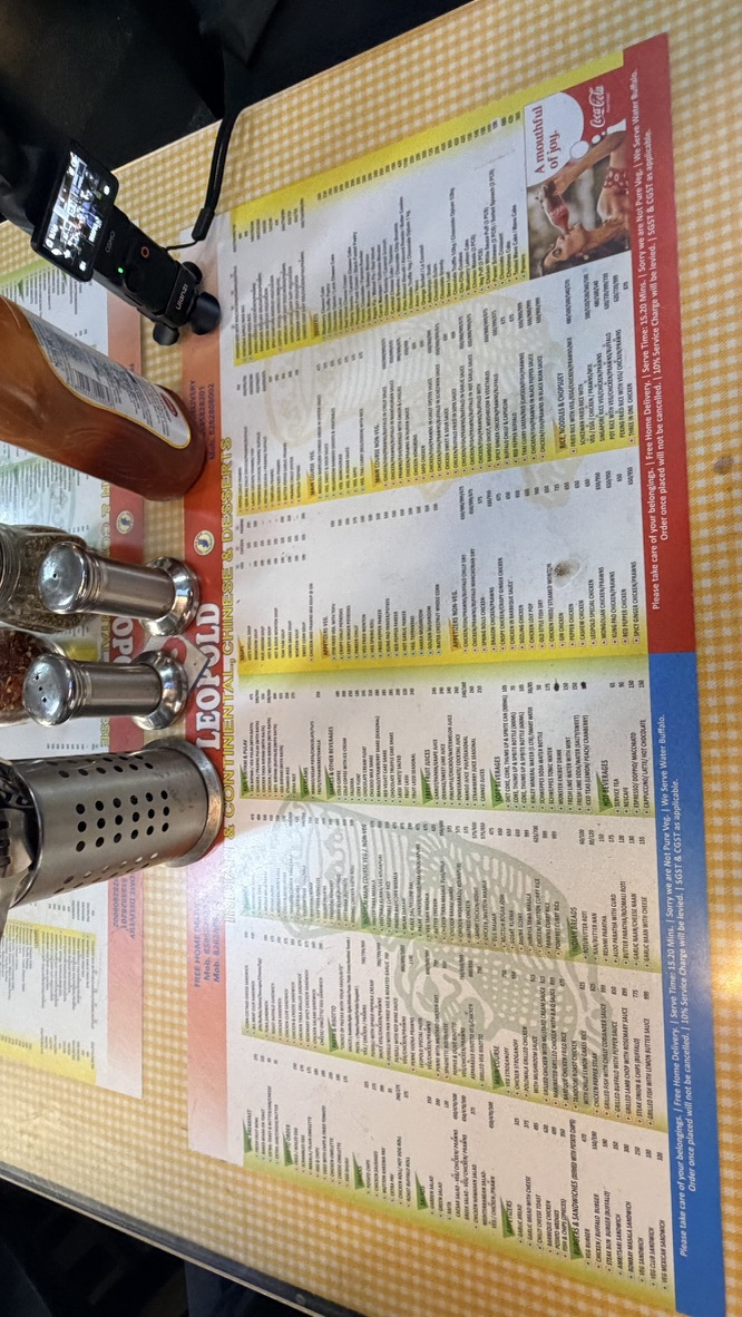 Printed food and drinks menu on a table at Leopold Café, Mumbai, India.
