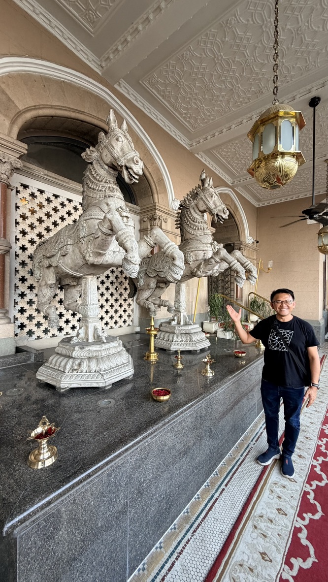 Traveller beside carved horse sculptures at the Taj Mahal Palace, Mumbai, India.