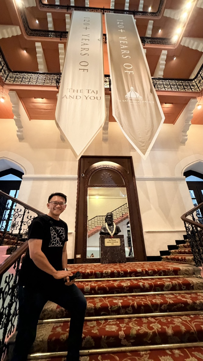 Traveller on the grand staircase beside Jamsetji Tata's bust, Mumbai, India.