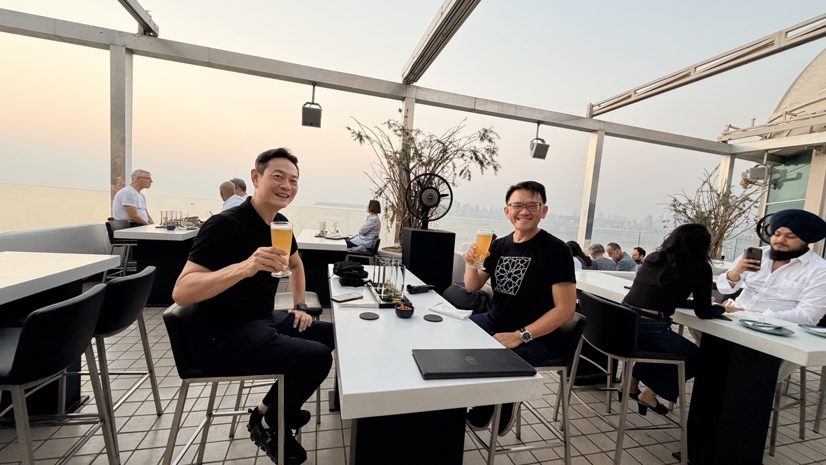 Two travellers with drinks at Dome rooftop bar, Mumbai, India.