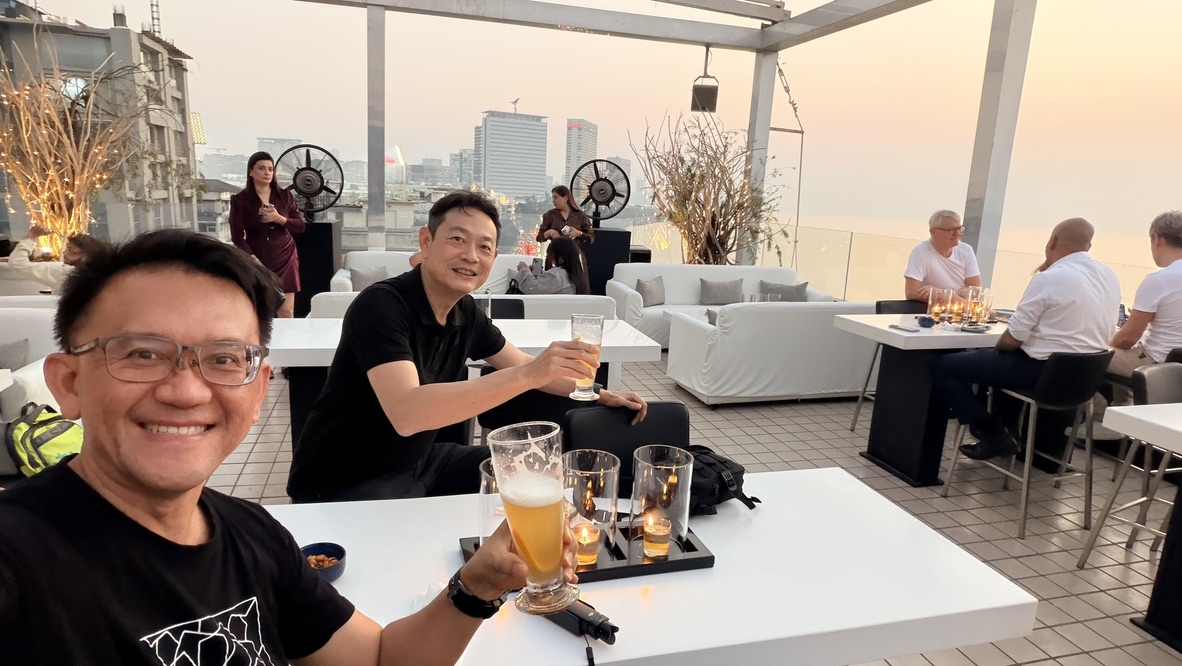 Two travellers raising beers at Dome rooftop bar, Mumbai, India.