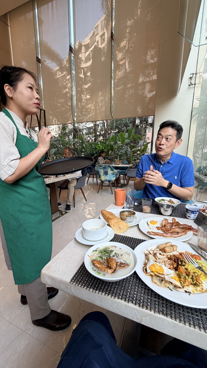Traveller speaking with a restaurant team member during breakfast in Mumbai, India.