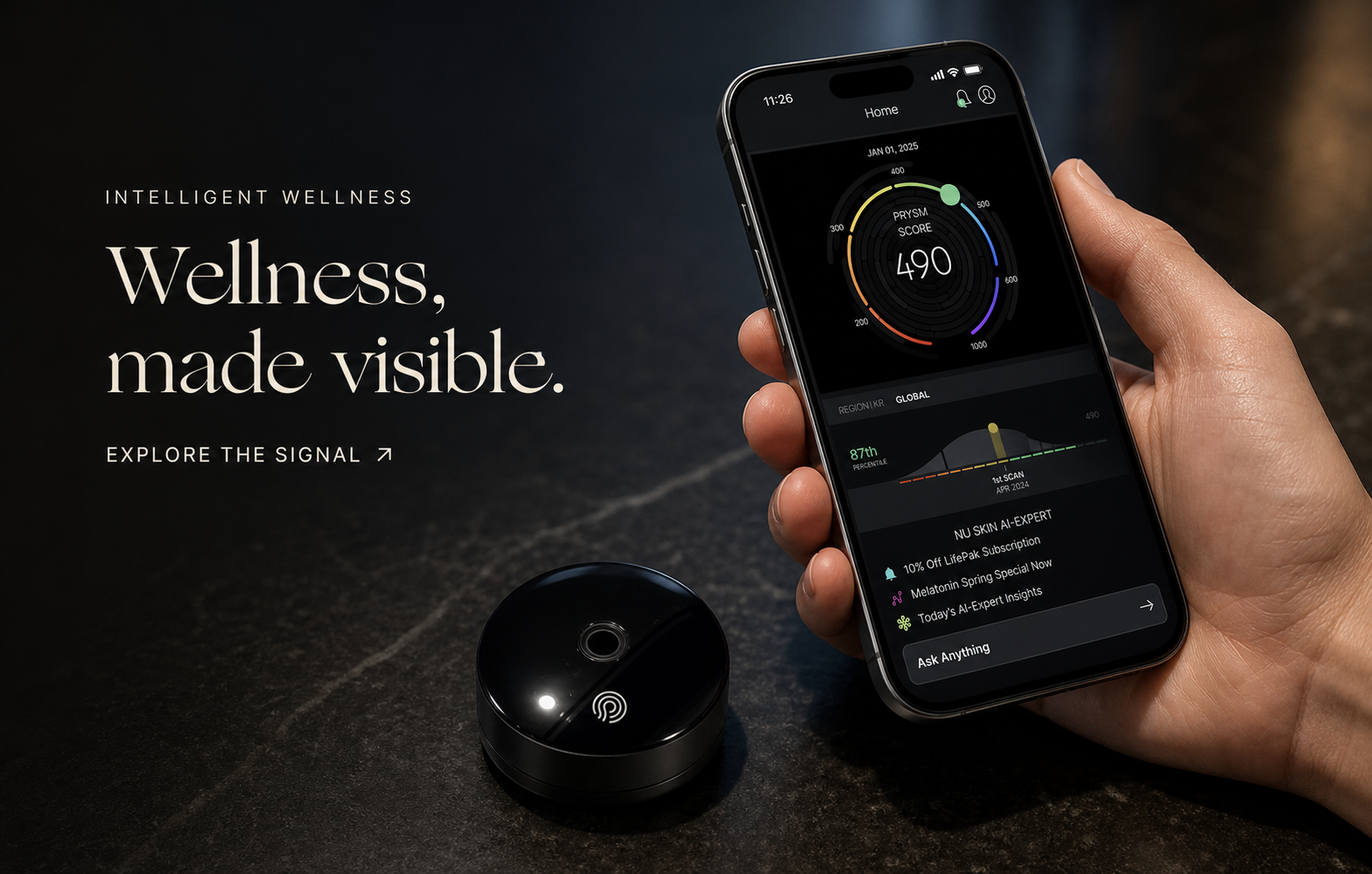 A hand holding a phone with a PRYSM wellness score beside the PRYSM iO device