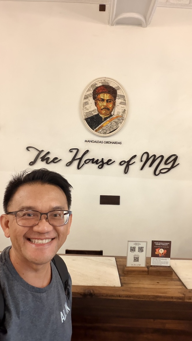 TOON at the reception desk beneath The House of MG sign in Ahmedabad