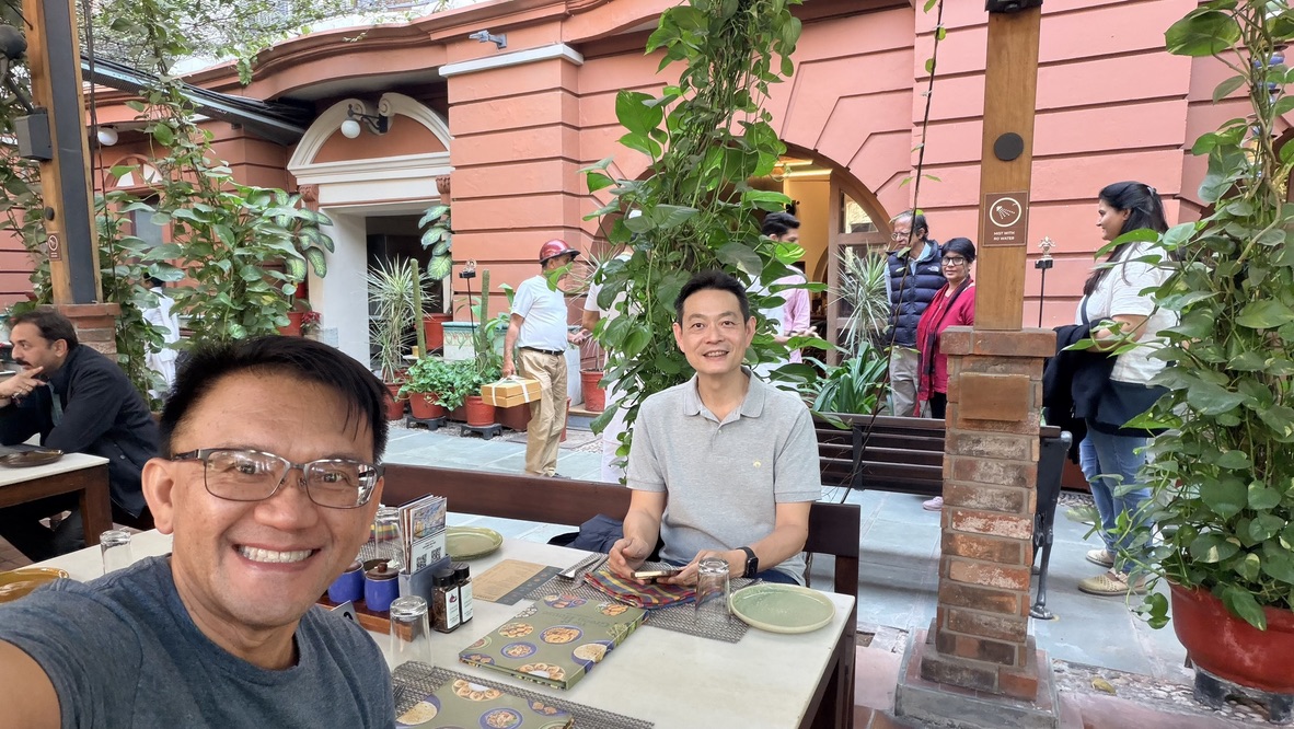 TOON and his travel companion seated at a leafy courtyard table at The House of MG