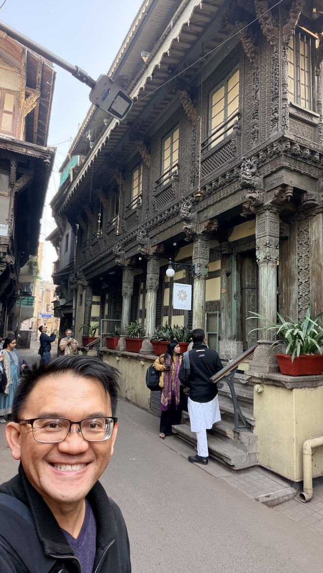 TOON beside an elaborately carved wooden haveli facade in a narrow pol lane in Ahmedabad