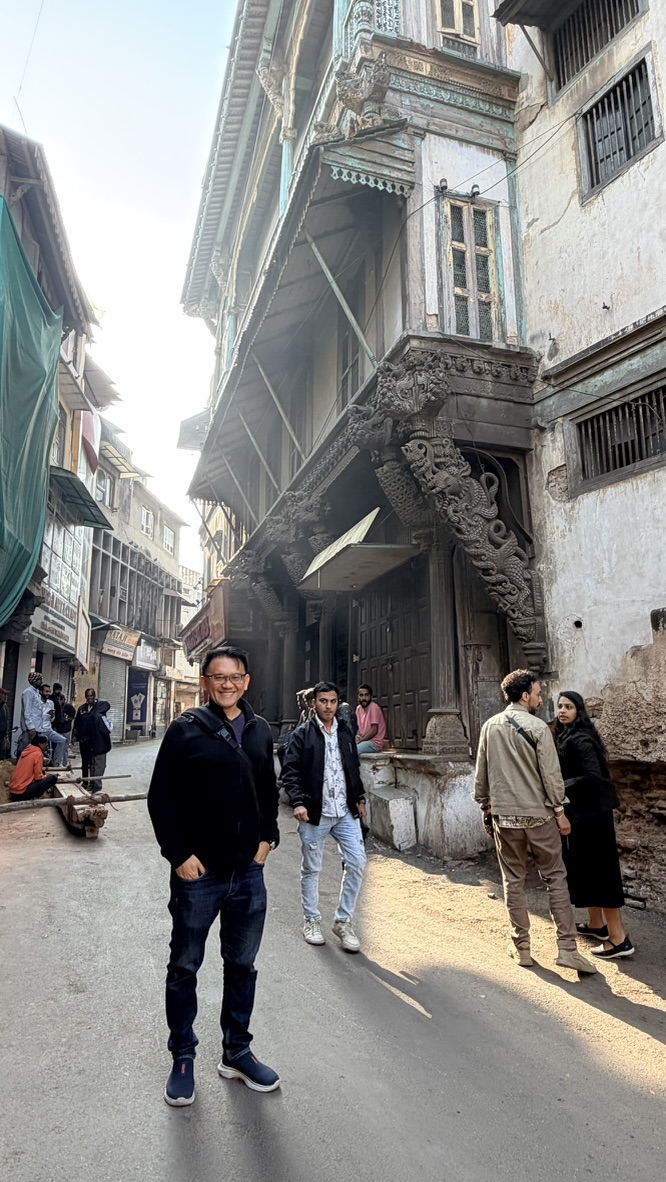 TOON standing in an old Ahmedabad pol lane beneath an ornate projecting wooden facade