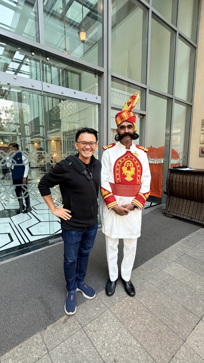 TOON standing with a traditionally dressed hotel doorman while departing ITC Narmada Ahmedabad