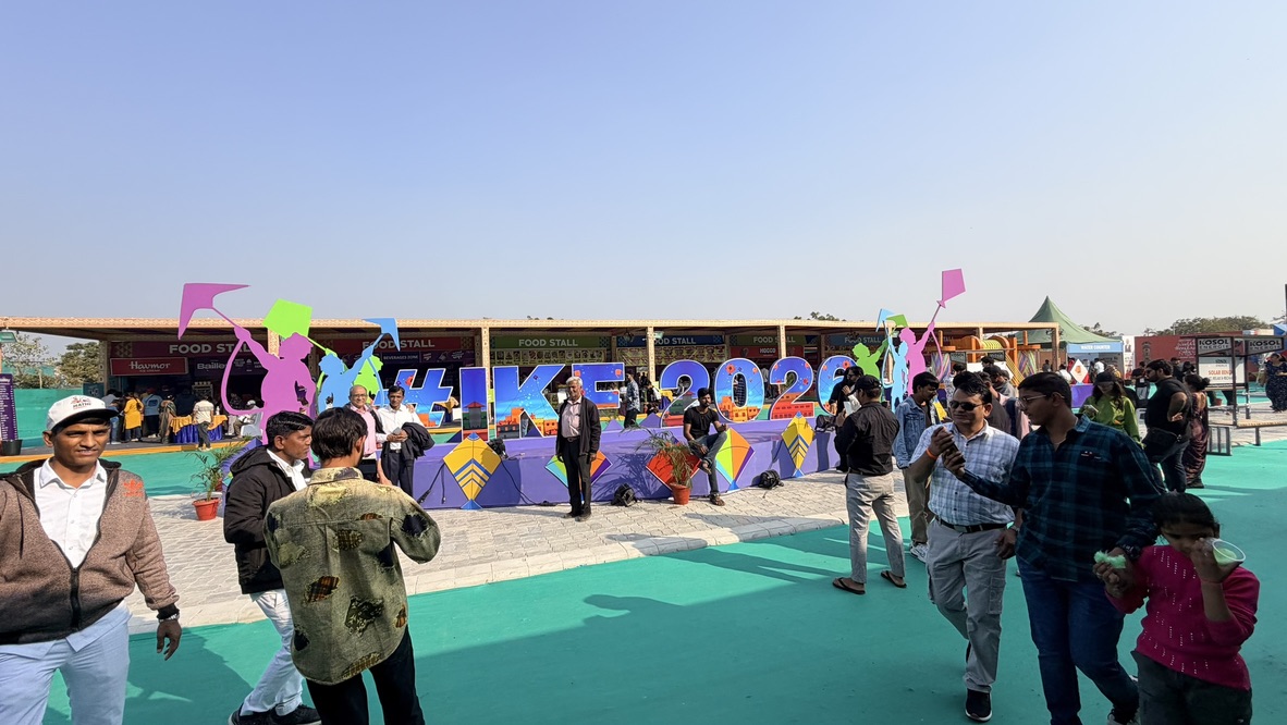Visitors gathered beside a colorful IKF 2026 display at the International Kite Festival in Ahmedabad