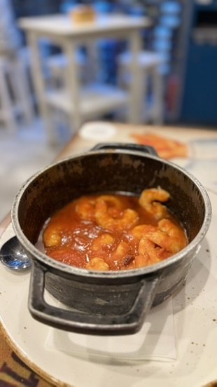 A small black pot holding pieces in a rich red sauce