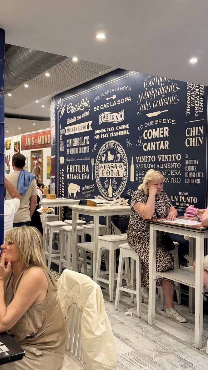 A busy Casa Lola dining room with tall white tables and blue graphic walls