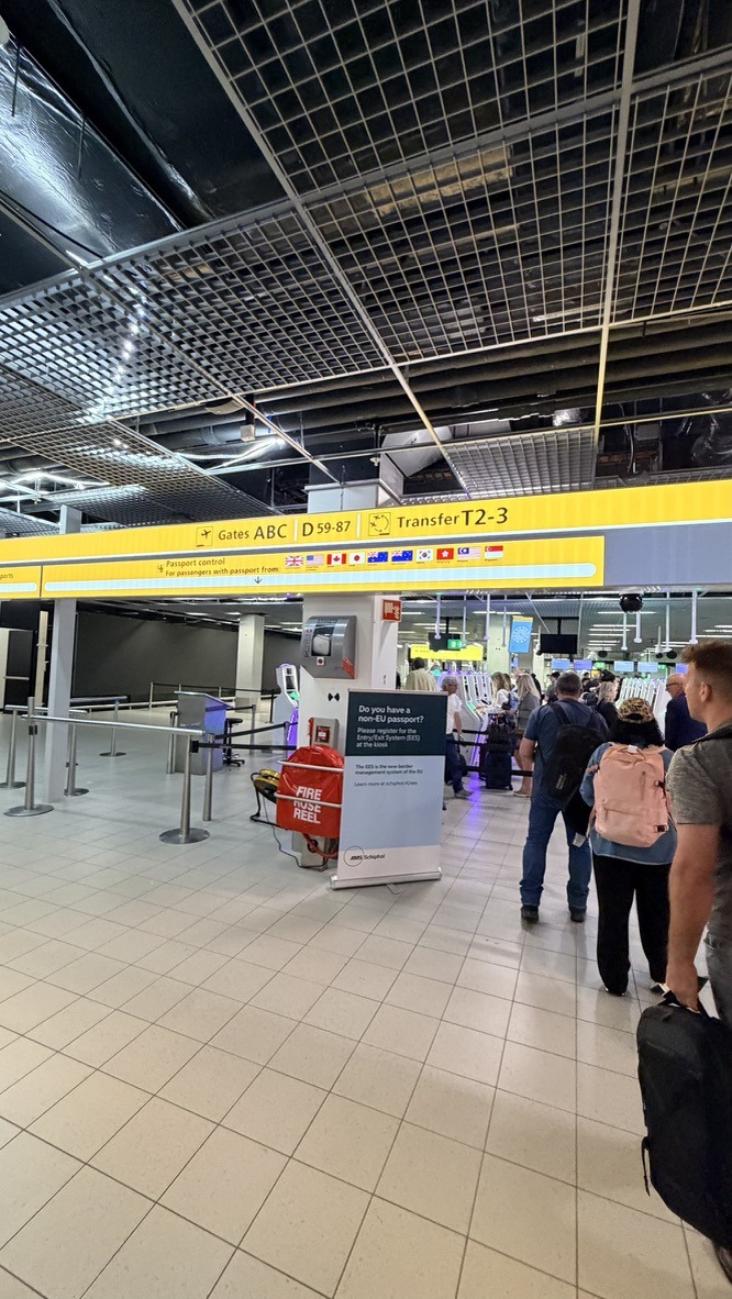 Yellow Schiphol signs directing travelers to passport control and transfer gates
