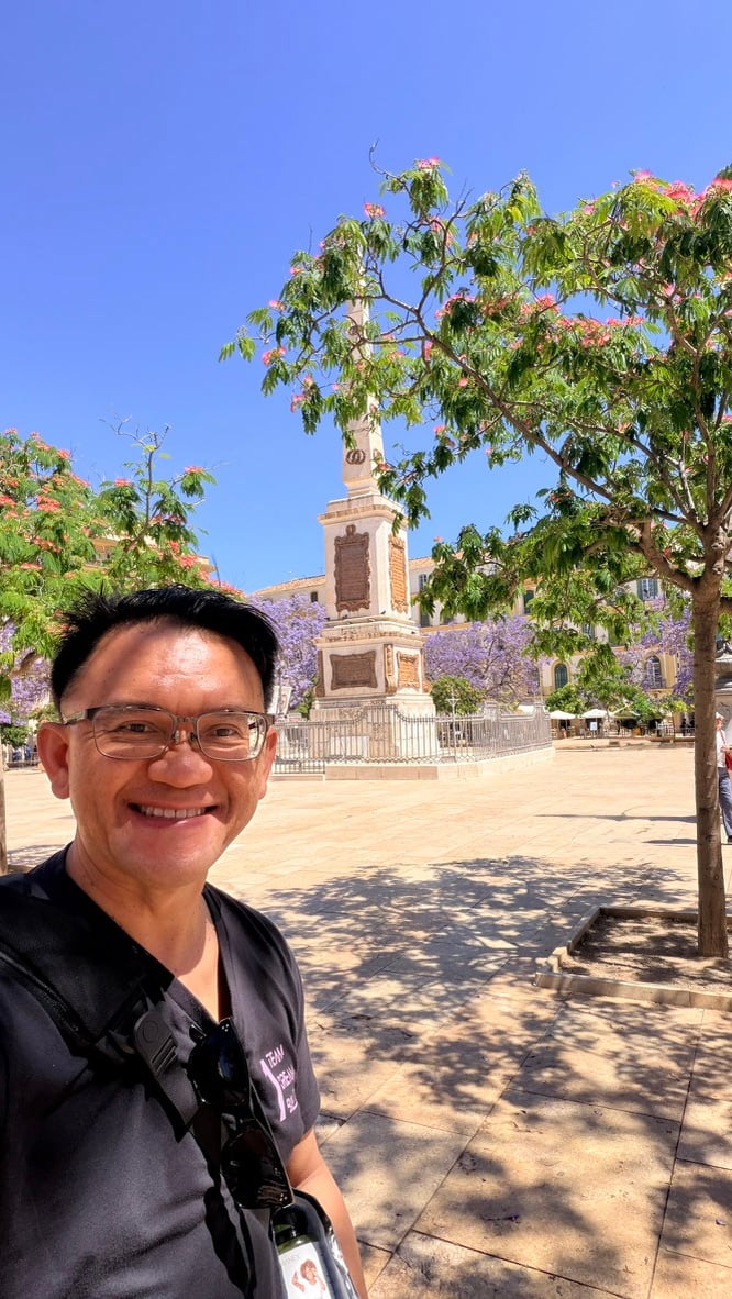 TOON smiling in Plaza de la Merced beneath flowering trees