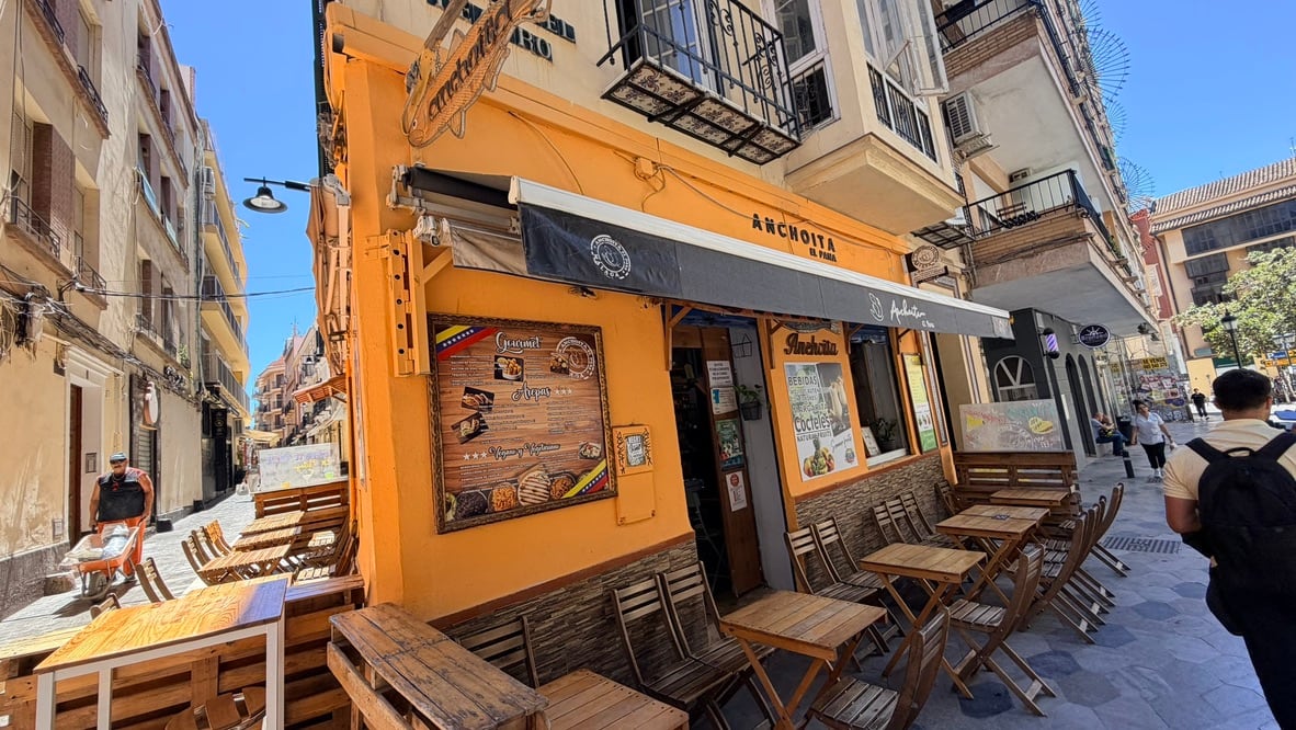 A bright orange corner café with outdoor tables in Málaga