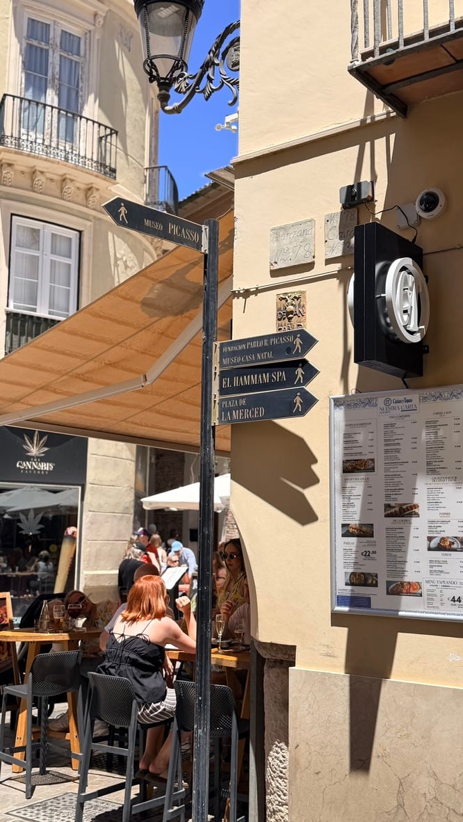 Street signs pointing toward the Picasso Museum, Picasso’s birthplace, the hammam, and Plaza de la Merced