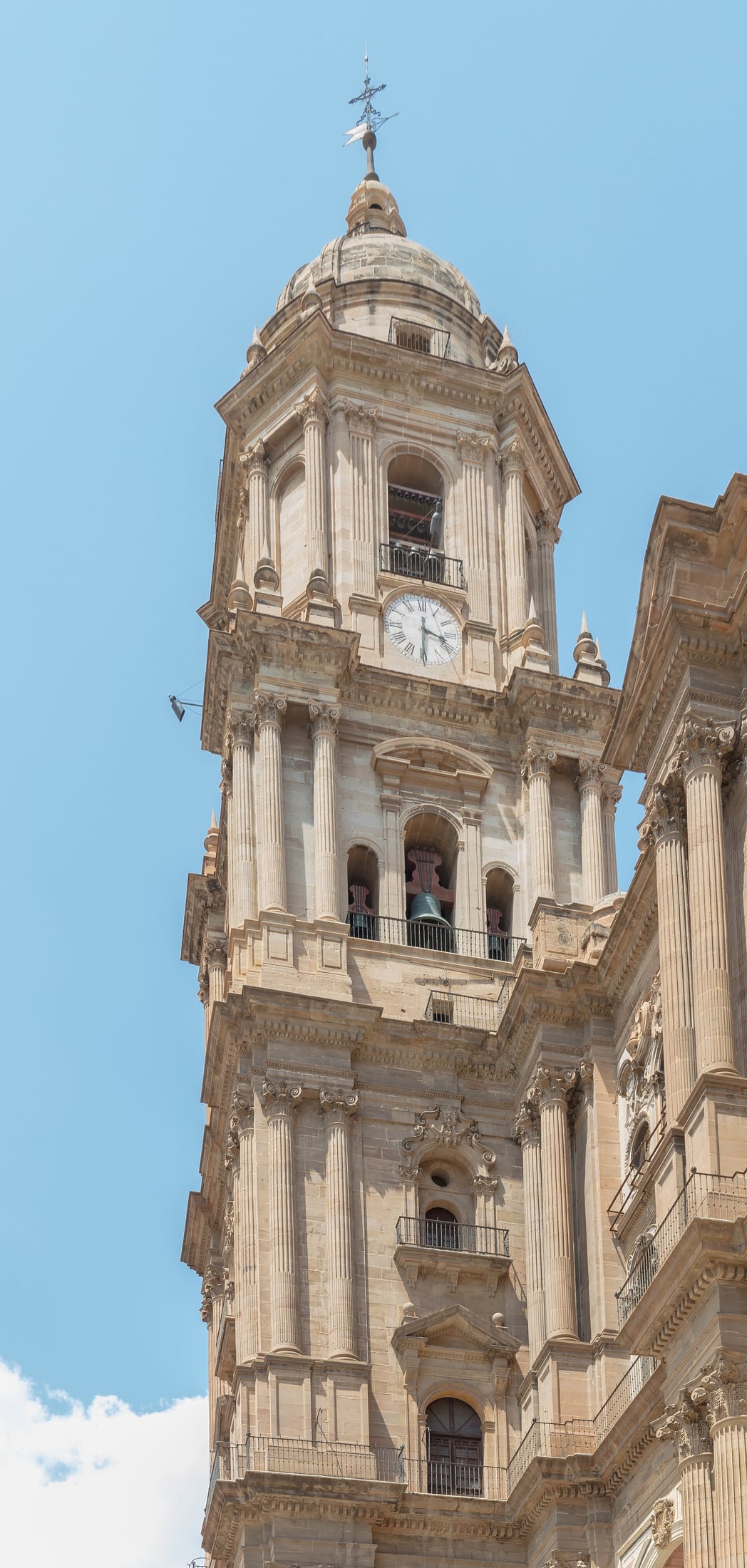The completed north tower of Málaga Cathedral against a blue sky